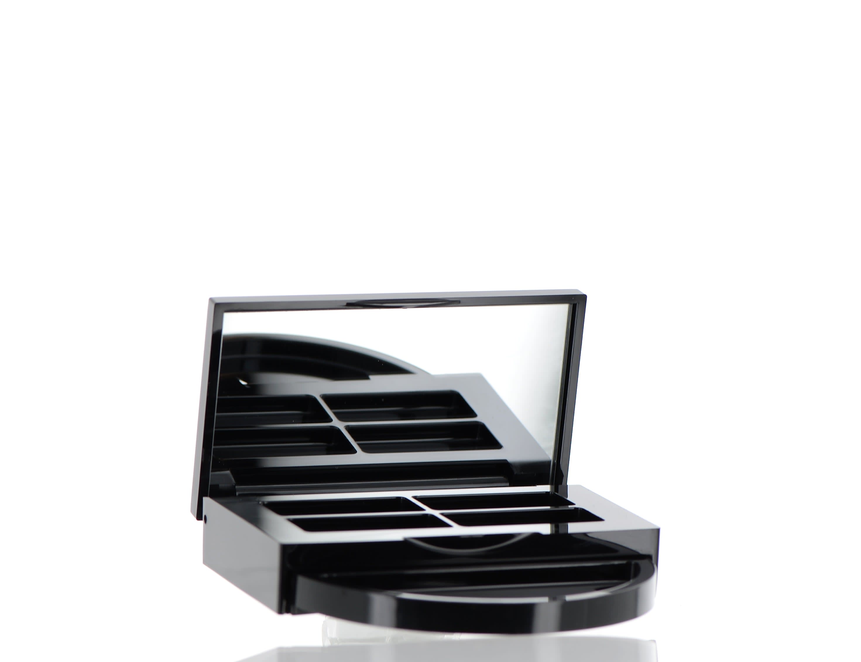 The image shows the APG Packaging 0.0oz ABS Compact (APG-CT-S016-BK). It is a sleek, black, circular compact case with a smooth, glossy finish. The compact is open, showcasing an empty interior designed to hold cosmetic products. The interior includes a circular recessed area where the product would be placed, and a mirror is attached to the inside of the lid. The compact has a minimalist and elegant design, suitable for various cosmetic applications.