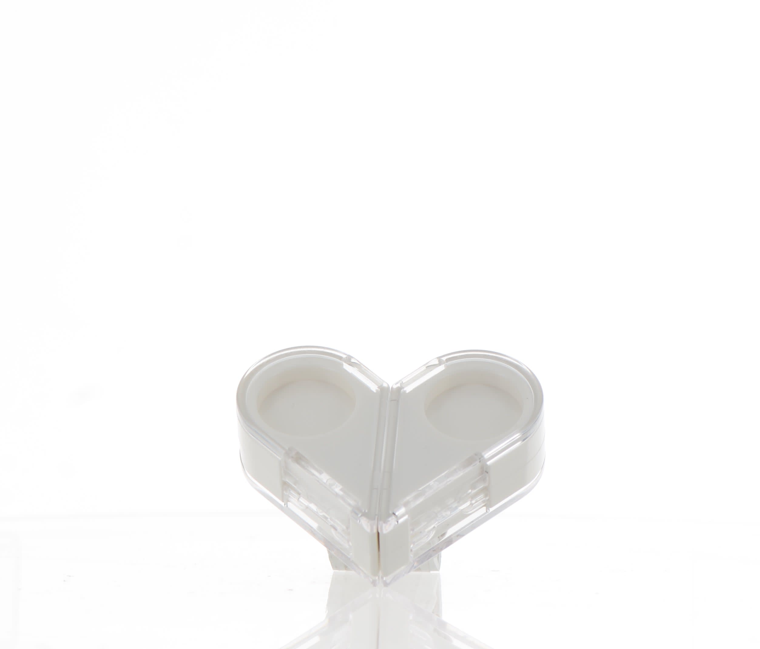 The image shows the APG Packaging 0.0oz Mixed Material Compact. The compact has a round, sleek design with a predominantly black exterior. The lid features a glossy finish, while the base appears to be matte. The compact is closed, and its surface is smooth and unembellished, giving it a modern and minimalist appearance.