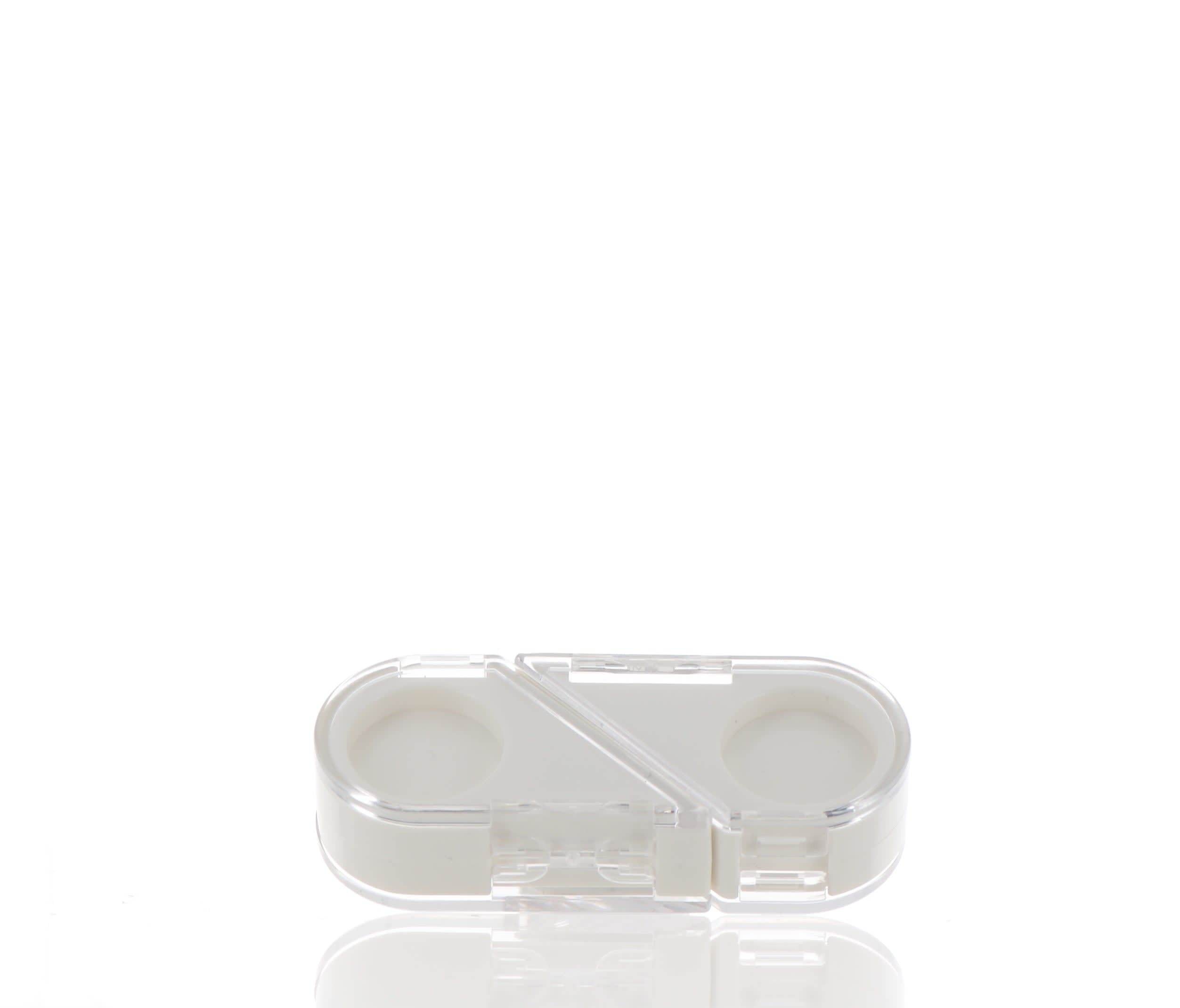 The image shows the APG Packaging 0.0oz Mixed Material Compact. It is a round, sleek compact case with a smooth, reflective surface. The compact is primarily black with metallic accents. The lid appears to have a glossy finish, and the bottom part is matte. The compact is closed, and its design suggests it is used for holding cosmetic products.