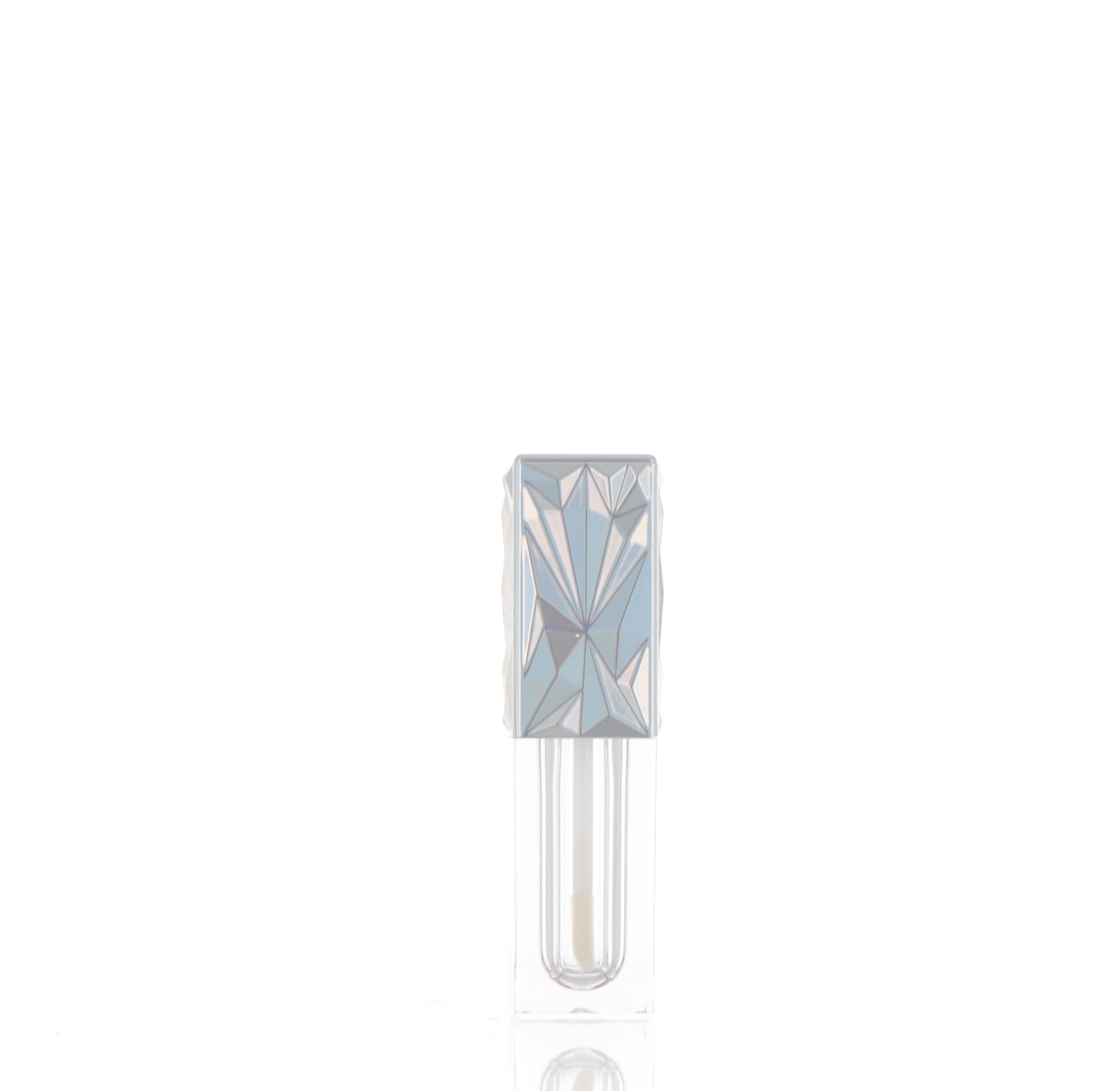 The image shows the APG Packaging 0.1oz Mixed Material Lip Gloss Tube. The tube is cylindrical and transparent, allowing the content inside to be visible. It has a shiny, metallic-colored cap that appears to be made of metal. The tube is small and compact, suitable for lip gloss. The overall design is sleek and modern.