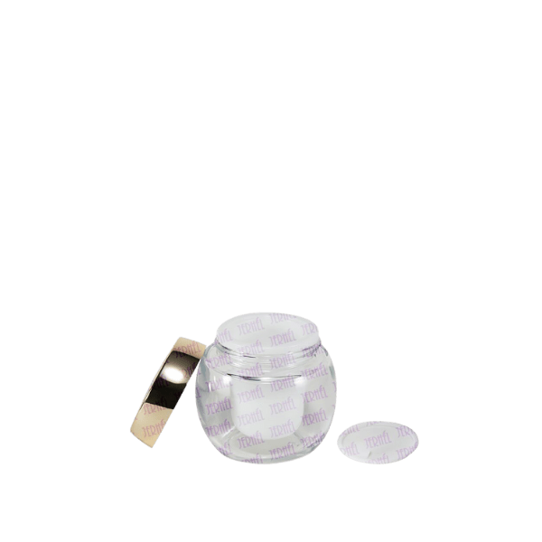 The image shows the Jerhel Plastics Inc. 1.7oz Glass Jar (JI-2192). The jar is clear and cylindrical with a thick base and smooth, straight sides. The lid appears to be made of a metallic material with a shiny, reflective surface, fitting securely on top of the jar. The glass is transparent, allowing the contents to be visible when filled. The overall design is sleek and modern.
