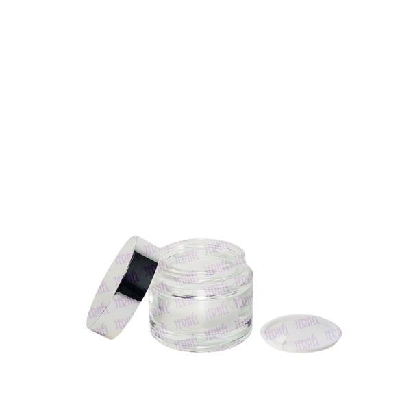 The image features the Jerhel Plastics Inc. 1.7oz Glass Jar (JI-2190). The jar is cylindrical with a clear glass body and a smooth surface. The lid is not shown in the image. The jar has a simple and elegant design suitable for various contents. The transparency of the glass allows the contents to be visible.