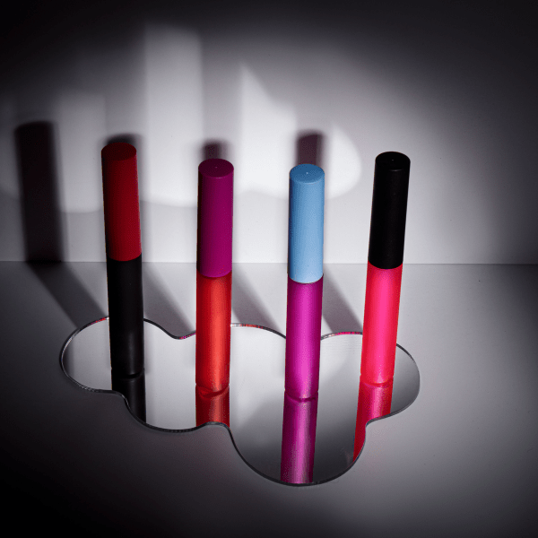 The image displays the Simex 0.3oz ABS Lip Gloss Tube (LG016). This is a small, cylindrical lip gloss tube with a transparent body, allowing the product inside to be visible. The tube has a sleek, glossy finish and is topped with a shiny, silver-colored cap. The overall design is elegant and compact, making it easy to carry and use.