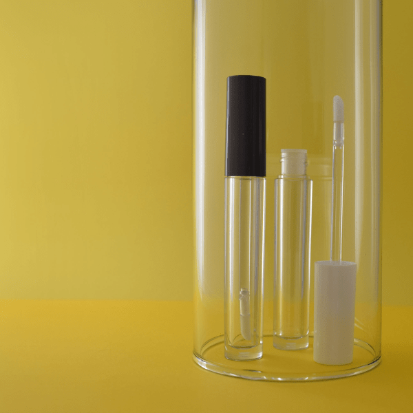 The image displays the Simex 0.3oz ABS Lip Gloss Tube LG016. The tube is transparent, showcasing the lip gloss contained within. It has a sleek, cylindrical shape with a smooth finish and an applicator wand attached to the cap. The cap is a contrasting color, providing a stylish and functional design. The overall appearance is modern and elegant, suitable for cosmetic use.