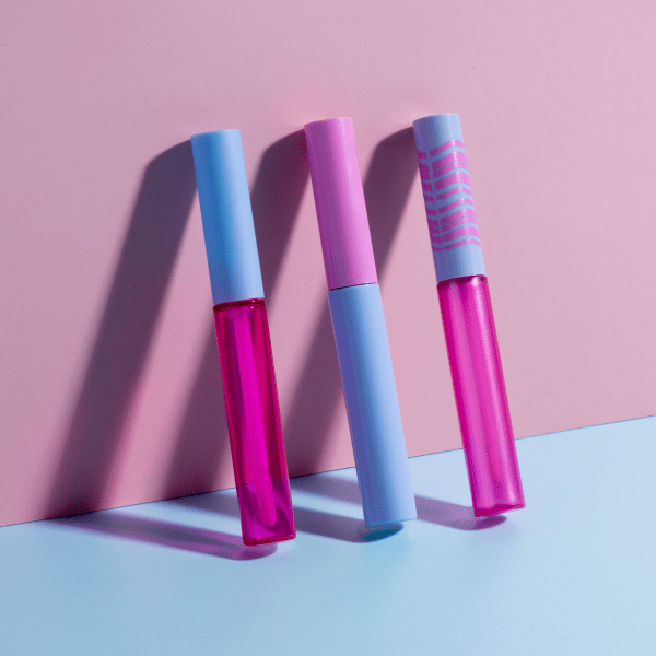 The image shows a SIMEX 0.3oz ABS Lip Gloss Tube (LG001). The tube is clear, allowing the contents to be visible, and has a sleek, cylindrical shape. It features a silver-colored cap with a smooth, reflective finish, providing a stylish contrast to the transparent body of the tube. The applicator, which is attached to the underside of the cap, is visible inside the tube. The overall design is modern and minimalist, making it an attractive packaging option for lip gloss products.