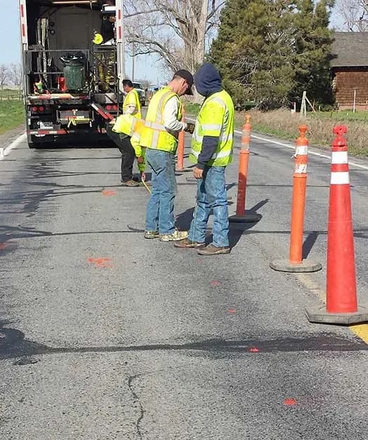 Three URETEK technicians on roadway blocked off by traffic cones