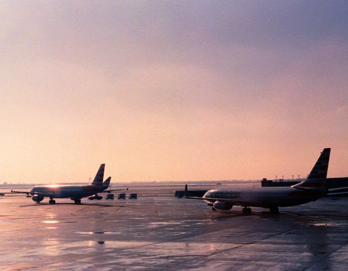 Airport at dawn with three planes on runway in distance
