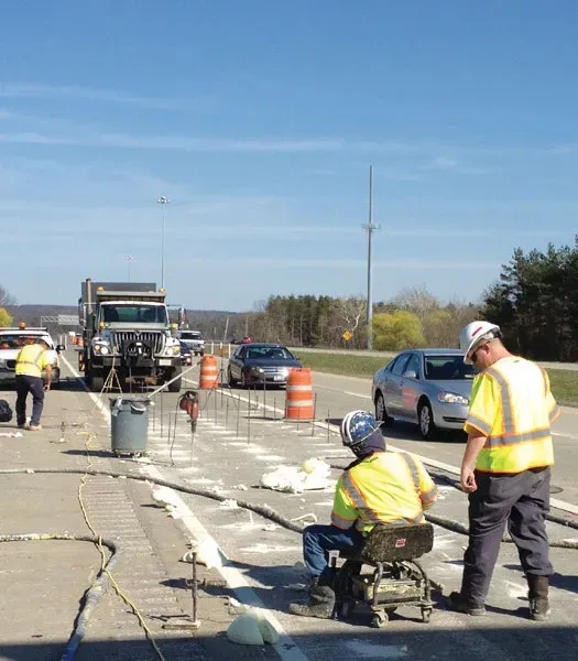 Two technicians in safety equipment work with concrete over a surface