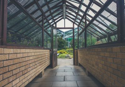 A long hallway leads to an open door revealing a greenhouse full of plants