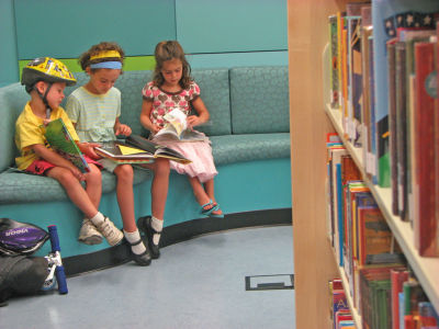 Three children sit reading books individually