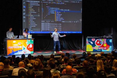 One person in the middle of the stage, two behind a desk