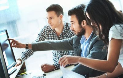 a group of people pointing at a computer screen