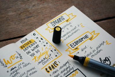 A picture of a notebook and a yellow felt pen with notes on motivational quotes written