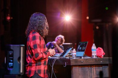 A picture of Addy Osmani and DJ Tobi on stage with Addy's face covered by his awesome curly hair