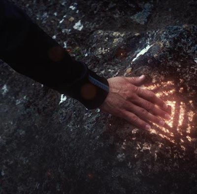 Man touching big rock with shining symbol