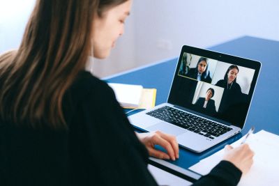 Woman sitting at laptop on video call with three others