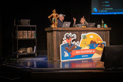 Chris Coyier and Brad Frost sitting at a desk on stage talking