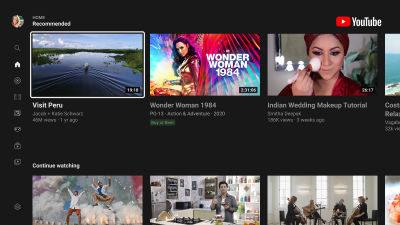 The interface of the YouTube TV app, displaying a dark-themed home screen with recommended videos. The layout is optimized for TV navigation, with large video thumbnails in two horizontal lists, and a sidebar menu on the left for browsing options.
