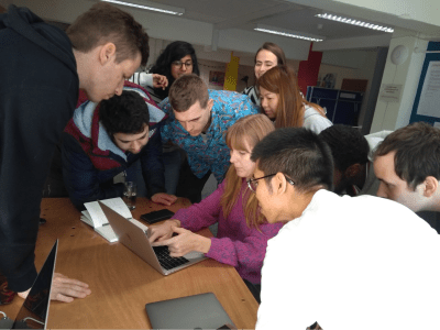 十名开发人员挤在一起使用mob编程解决问题的笔记本电脑。