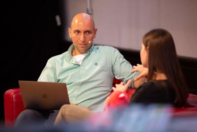 Two people on a sofa on stage talking