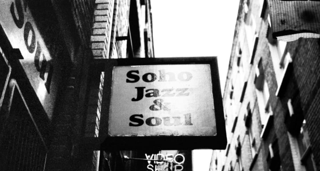 The Soho Jazz & Soul sign above a narrow street, in black and white