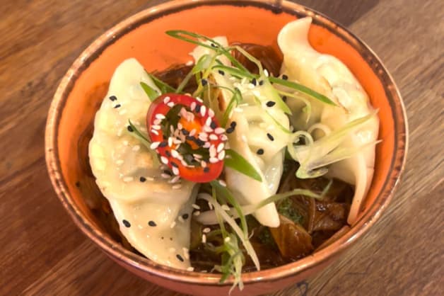 A bowl of dumplings topped with chilli and spring onion