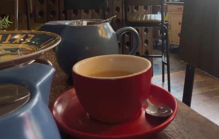 A pot of tea with a red cup and saucer