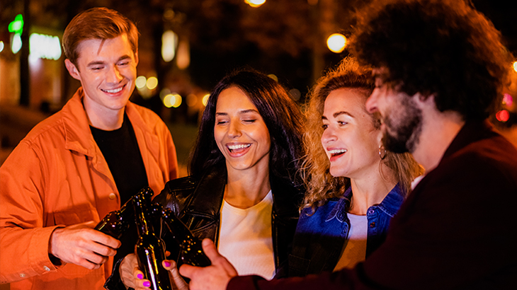 Group of four young people enjoying a night out in London – toasting drinks during a London experience