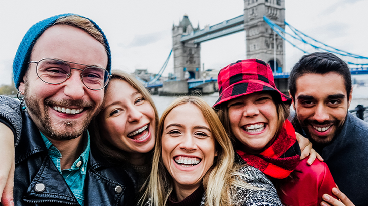 Group of young friends enjoying a fun day out in London with Tower Bridge in the background