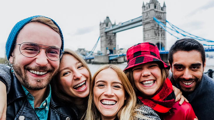 Group of friends enjoying London sightseeing with Tower Bridge and Thames in the background