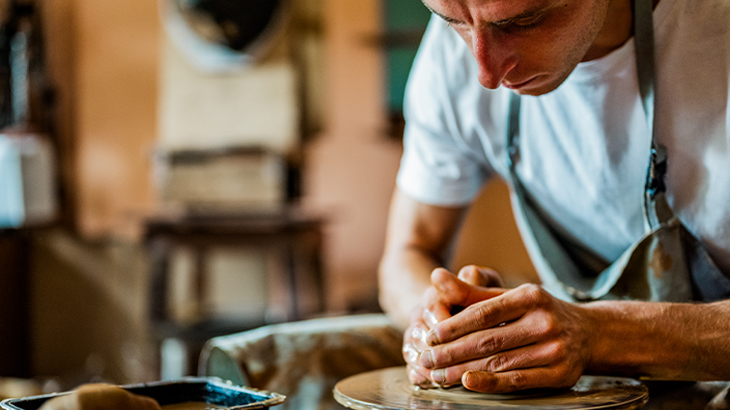 Artisan creating pottery on a wheel in a pottery workshop, hands shaping clay