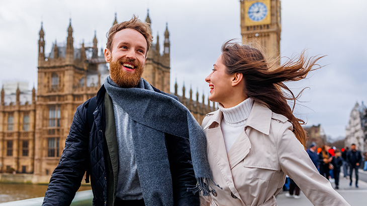 Couple walking across London bridge with Big Ben and Houses of Parliament in the background