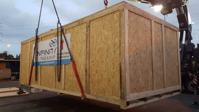 A large, heavy-duty custom shipping crate, engineered by Infinity Pack & Ship to protect industrial machinery for international transit.