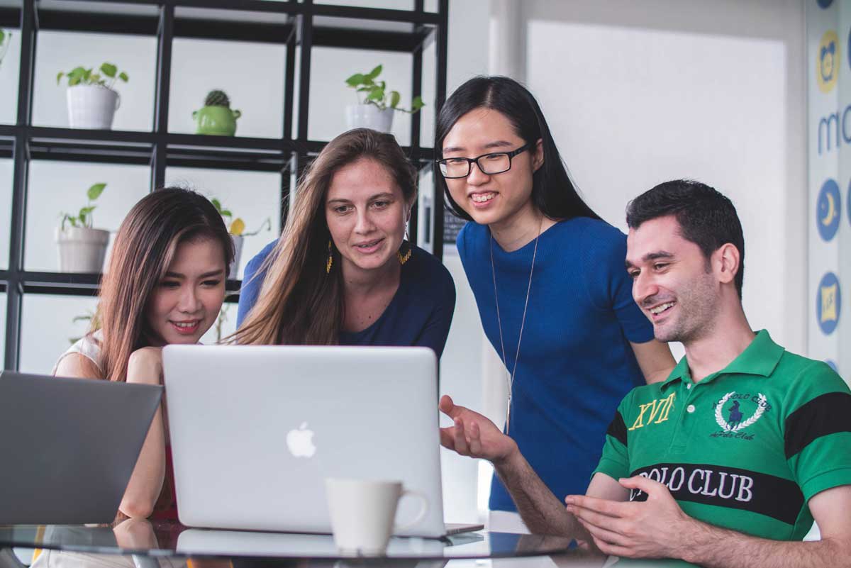 Employees collaborating around laptop