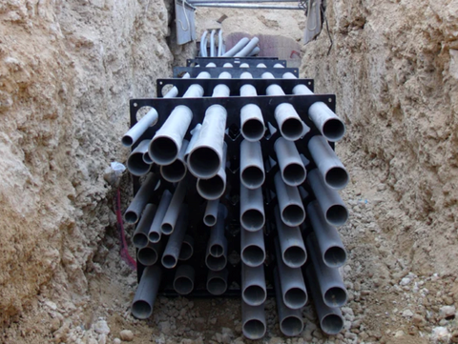 HDPE duct bank spacers supporting conduit during concrete pour, showing durable recycled material construction and precise spacing configuration