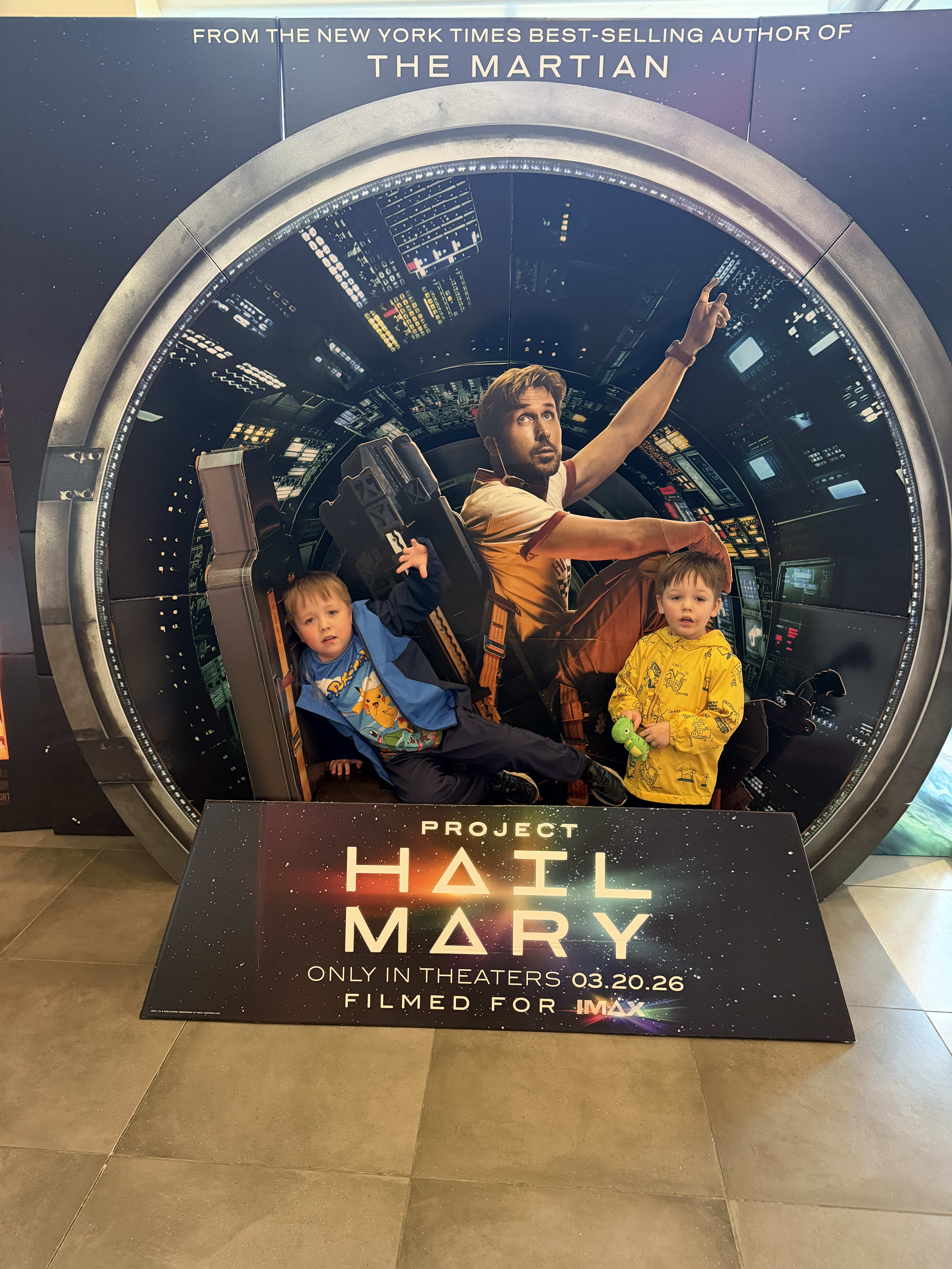 Ryan and Owen in front of a cardboard standee of Project Hail Mary.