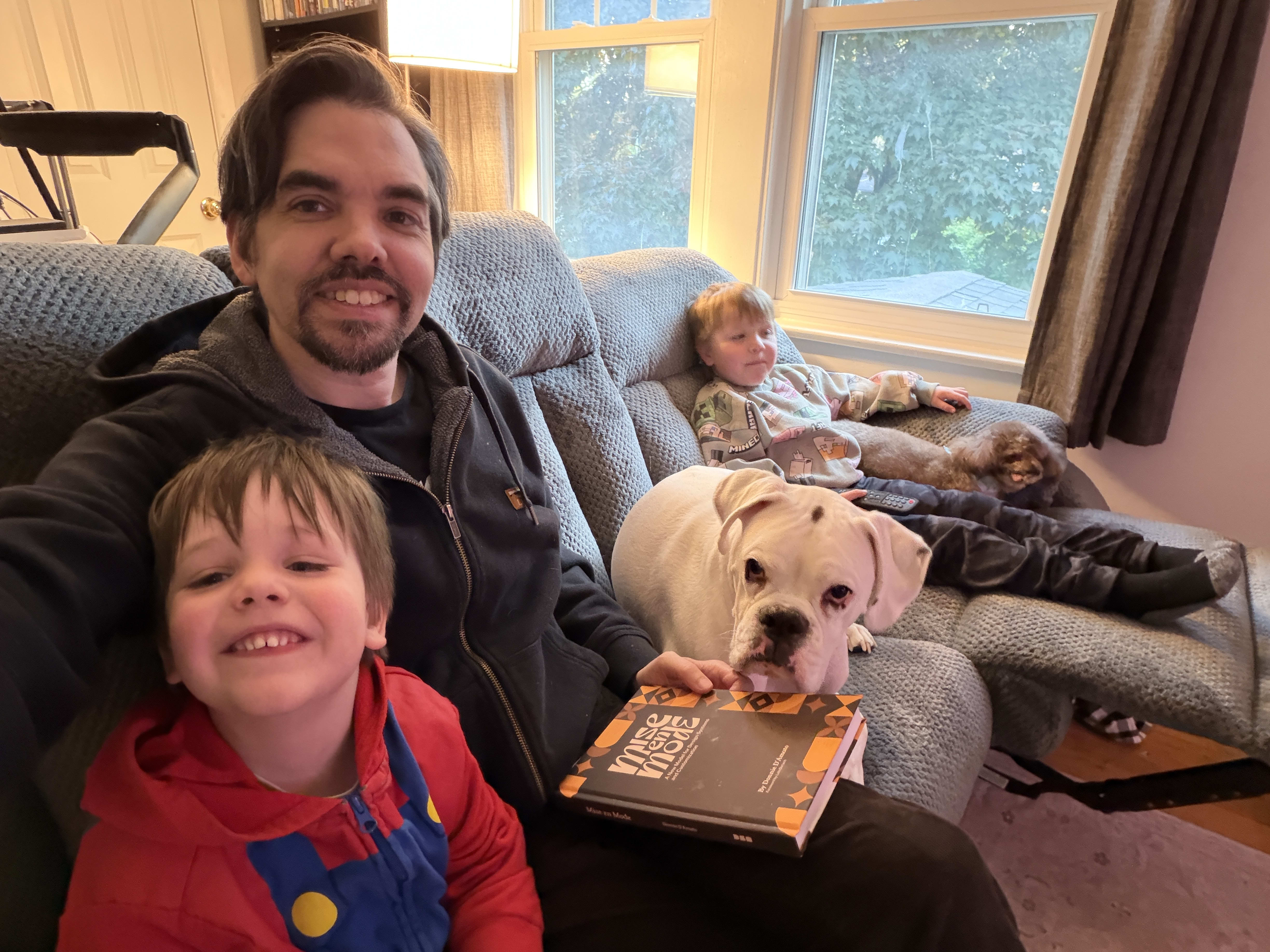 Owen, Mike, Mario (a white boxer) and Ryan enjoying a new gray couch with reclining seats.