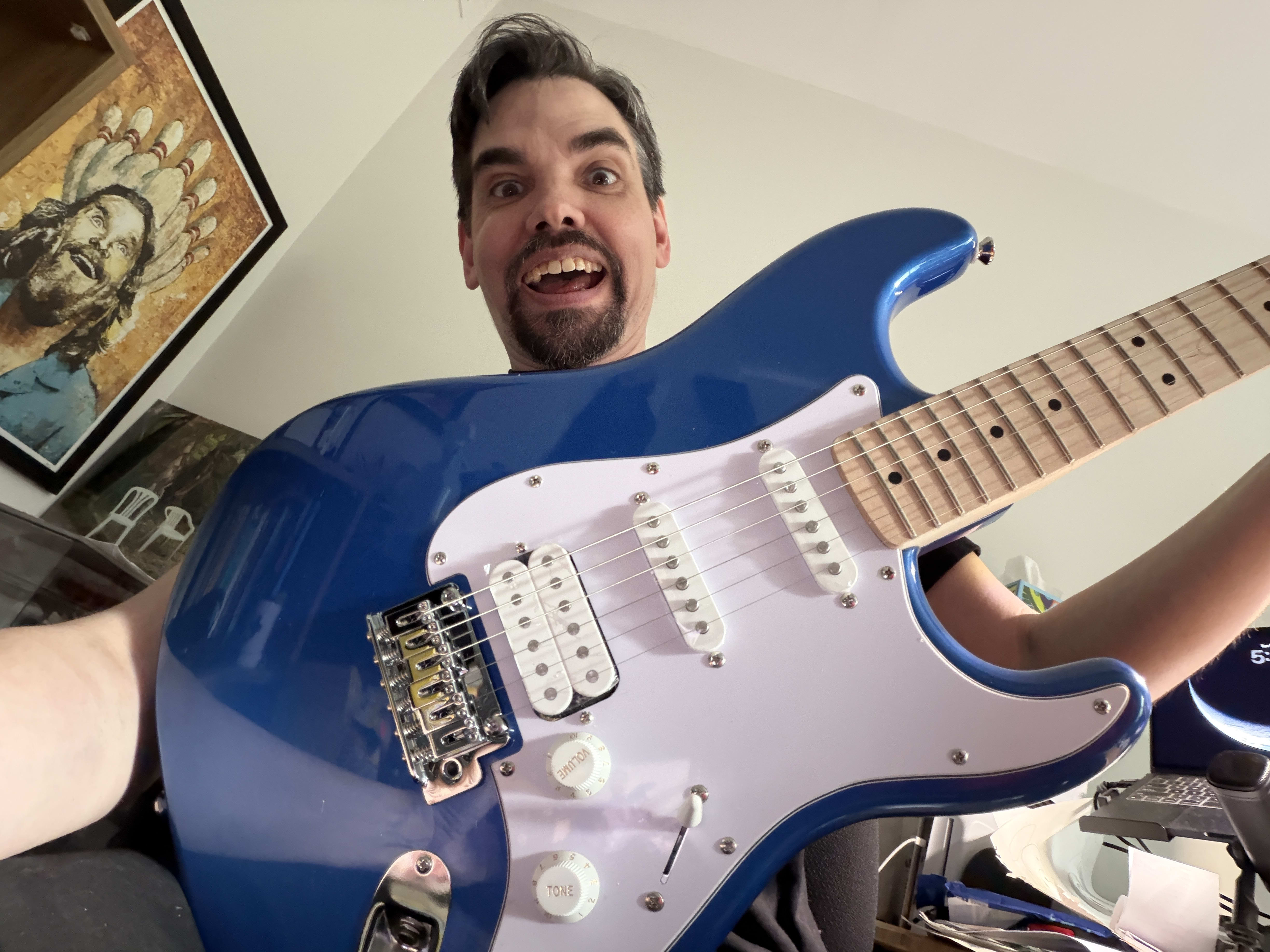 Mike holding a blue and white Fender Squire Stratocaster.