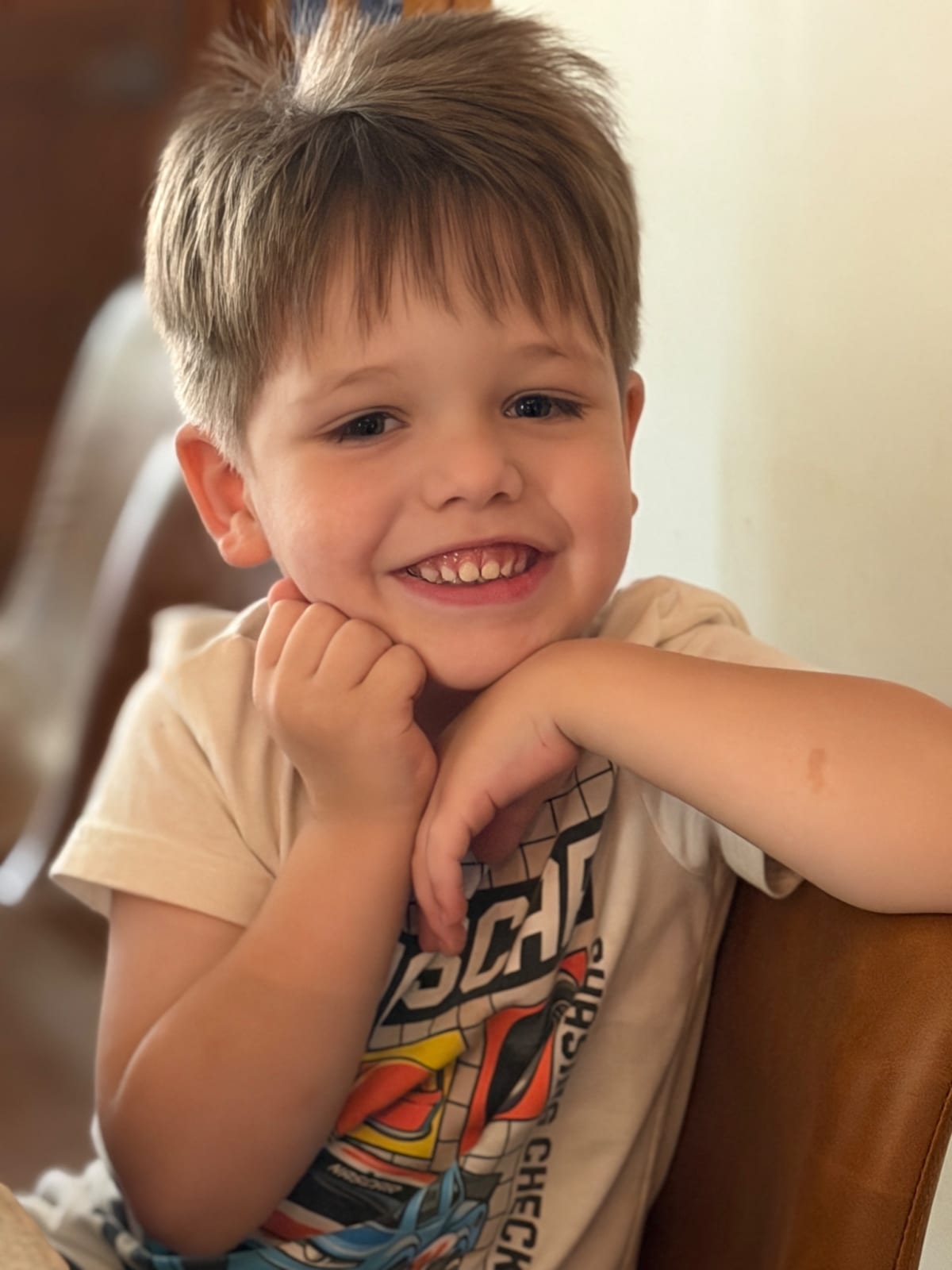 Owen with both hands under his chin looking all cute.