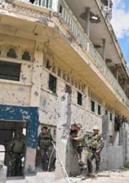 Soldiers stand around a war-damaged building in the Philippines.