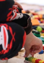 Children play on the floor with colourful lego pieces.