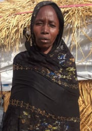 Portrait of Maryamu standing outside a dwelling at the IDP camp
