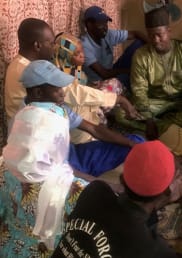A group of men sit in a circle on the floor.