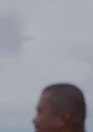 A man walking past a tall thin tower.