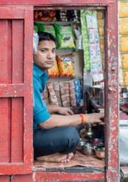 A Nepalese man sits on the floor in his small shop