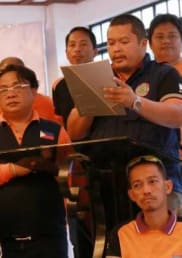 A Filipino man reads to a group meeting