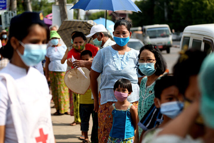 People wait at a COVID-19 health check station in Yangon, Myanmar