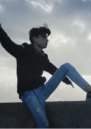 Young man sits on a wall, his silhouette framed by the sky