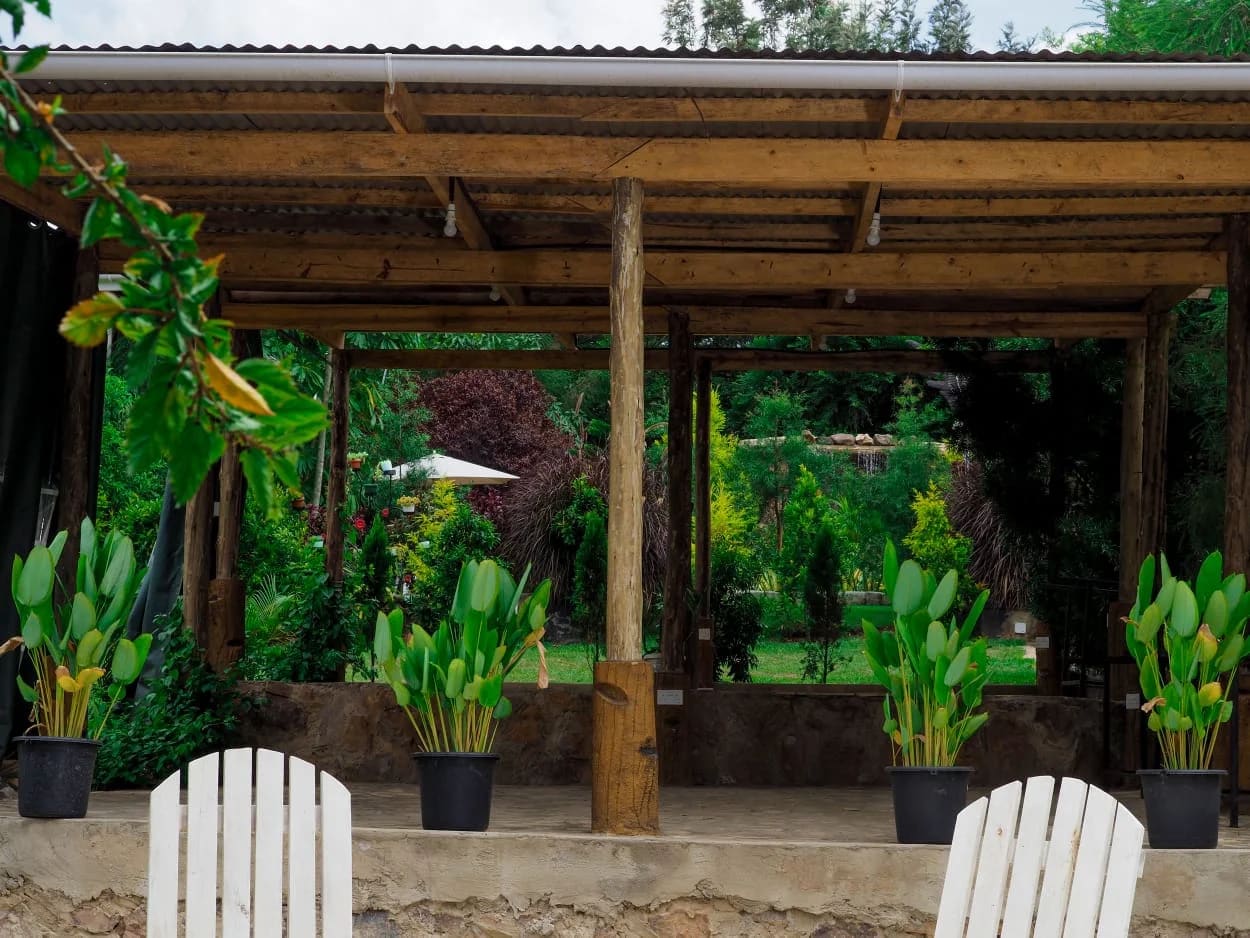 Wooden patio pavilion with potted plants and white chairs