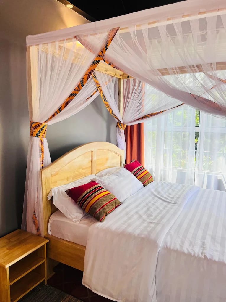 Bedroom with a wooden bed, striped bedding and a white canopy net